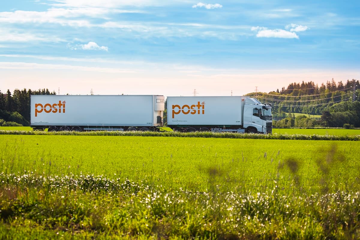 Posti van driving through a lush green field