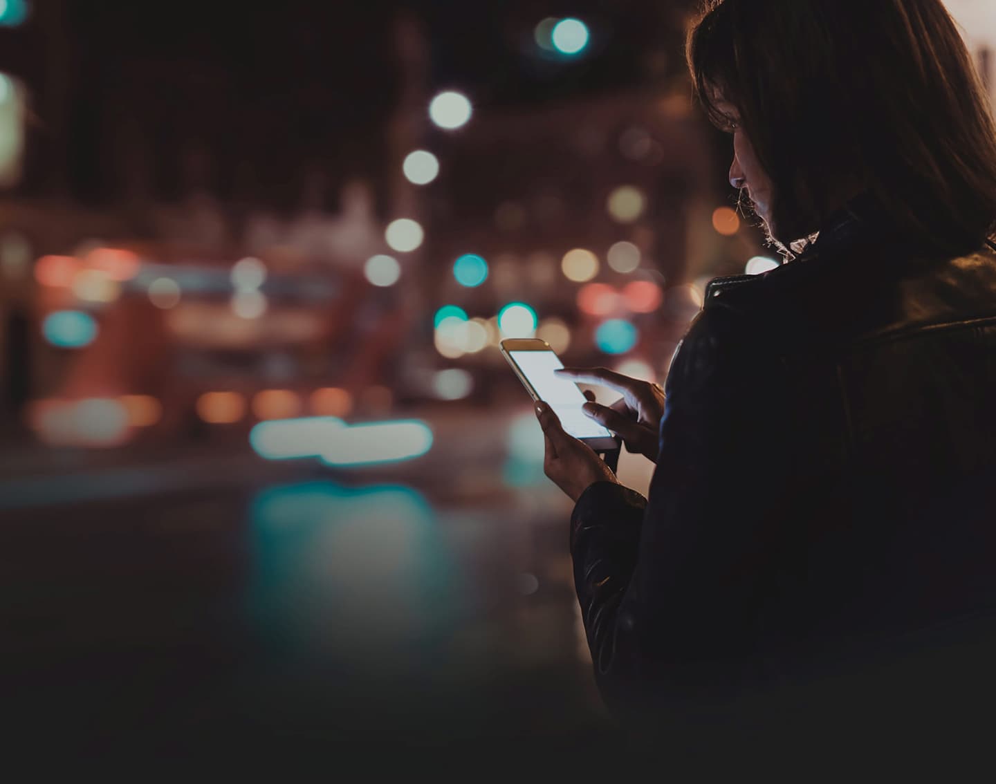 Woman checks phone with blurred lights in background