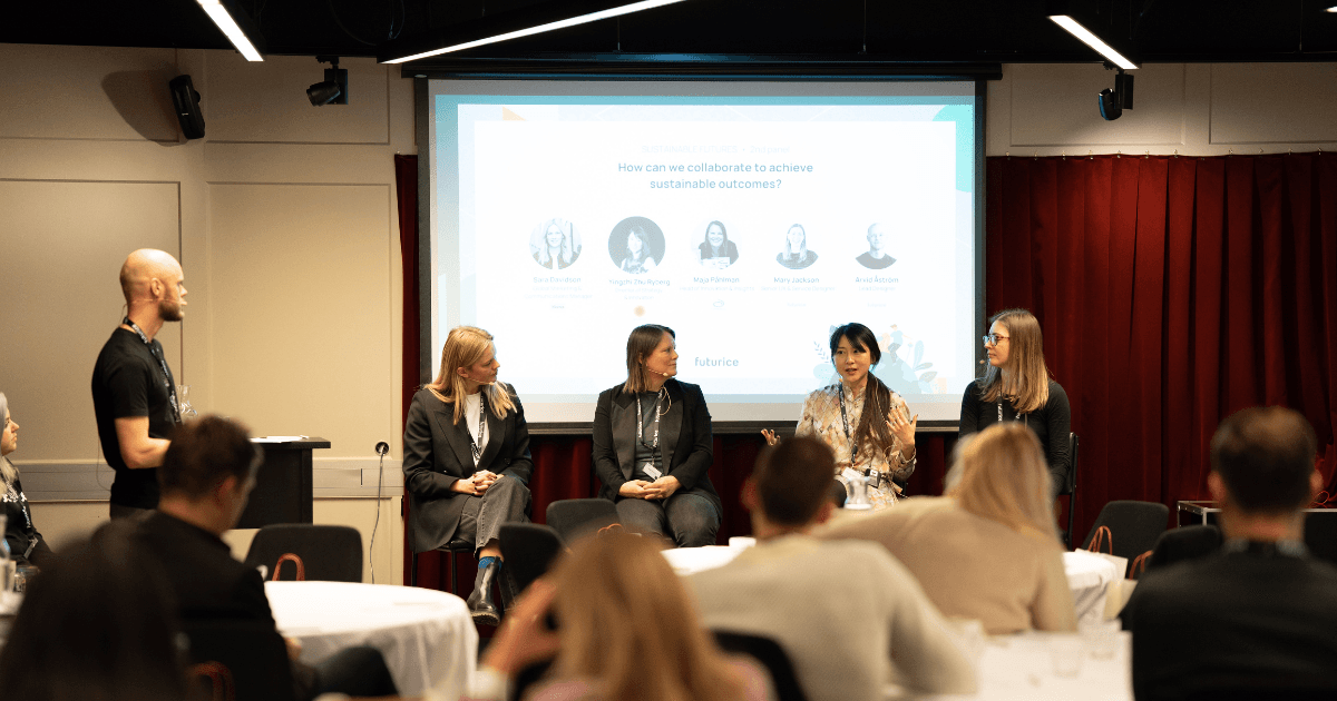 Panel discussion on sustainability collaboration with four speakers seated on stage and a moderator standing nearby.