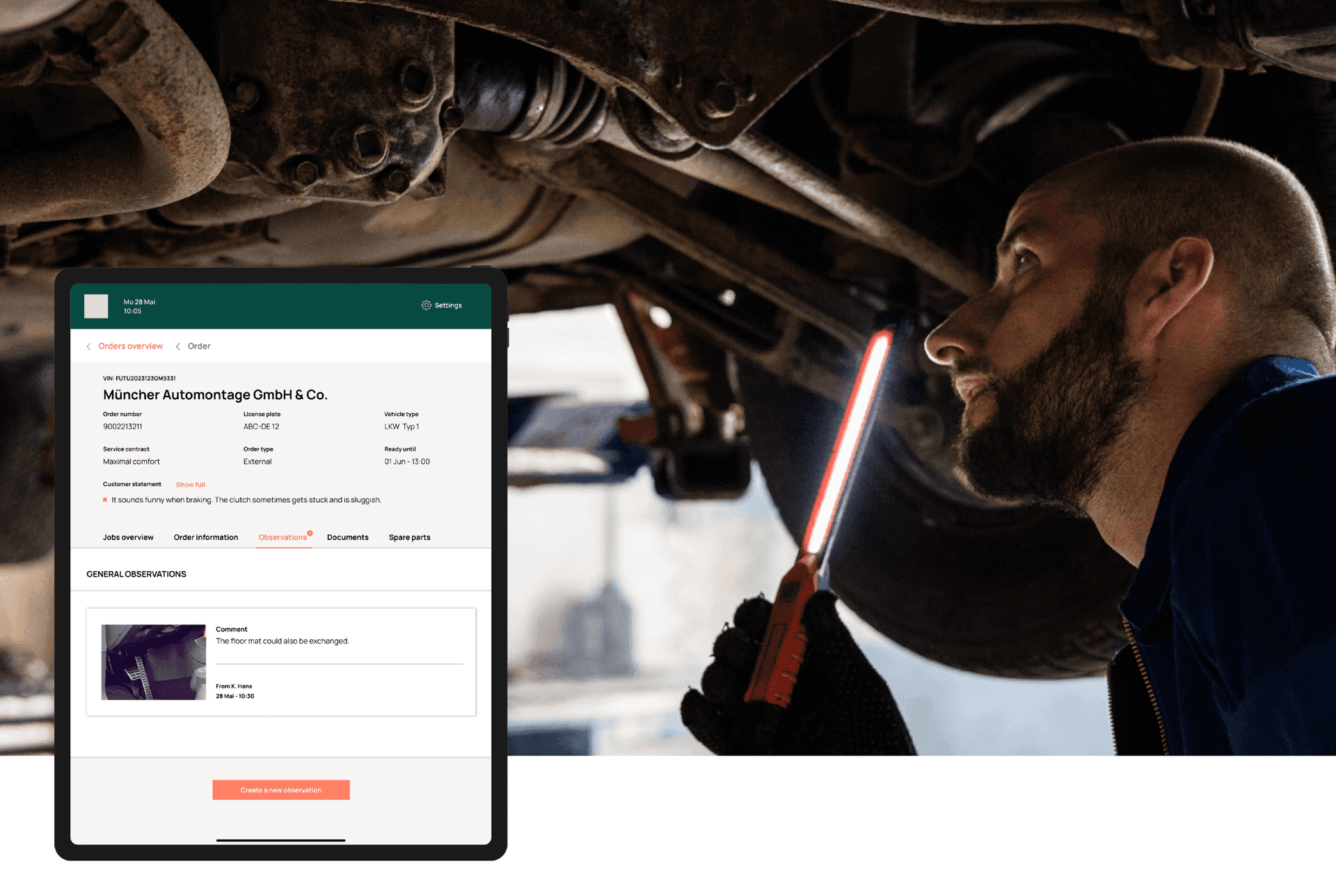Mechanic inspecting car undercarriage with work light while viewing repair order details on tablet screen.