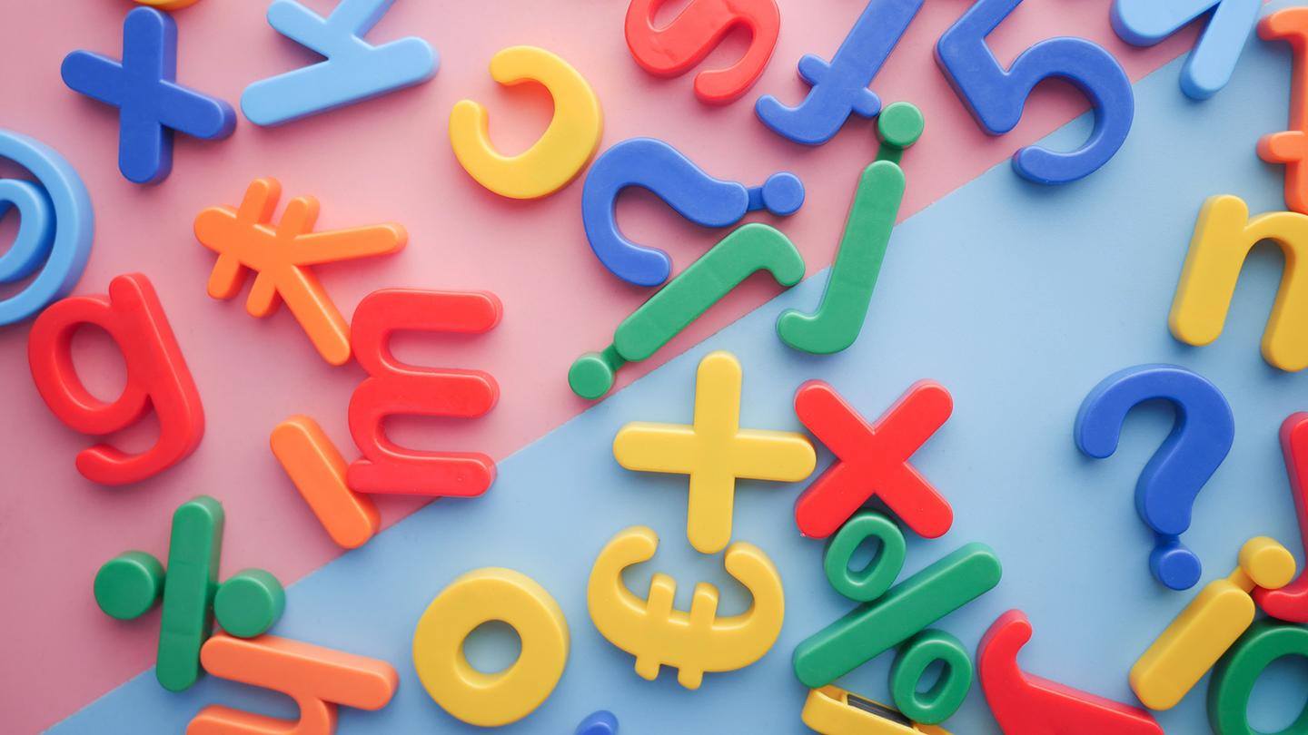 An assortment of various colorful children's magnetic letters scattered on a pastel background
